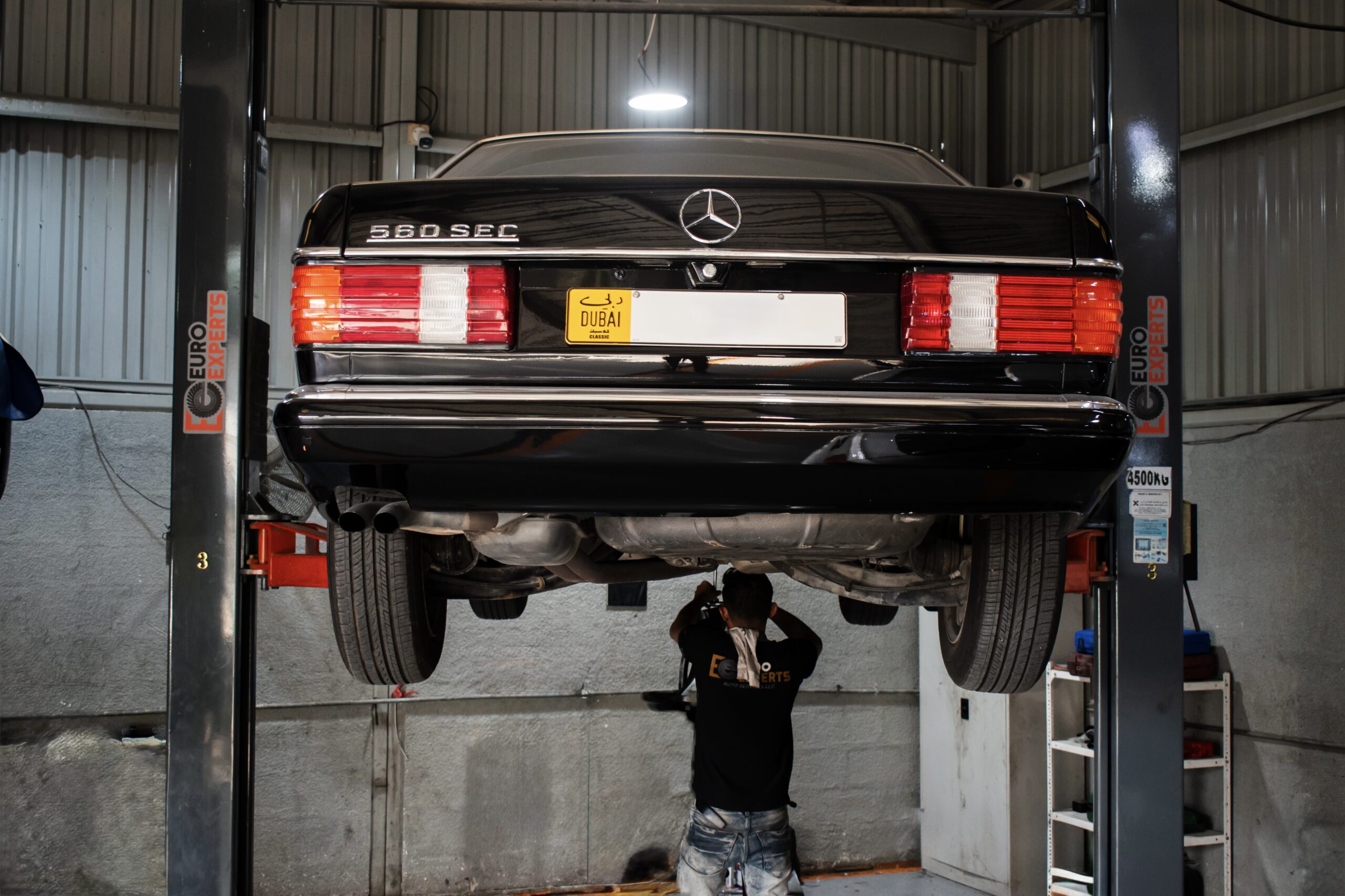Mercedes 560 SEC raised on a workshop lift at Euro Experts in Dubai